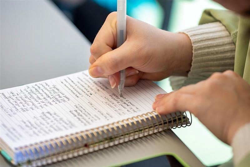 Hands writing in journal.