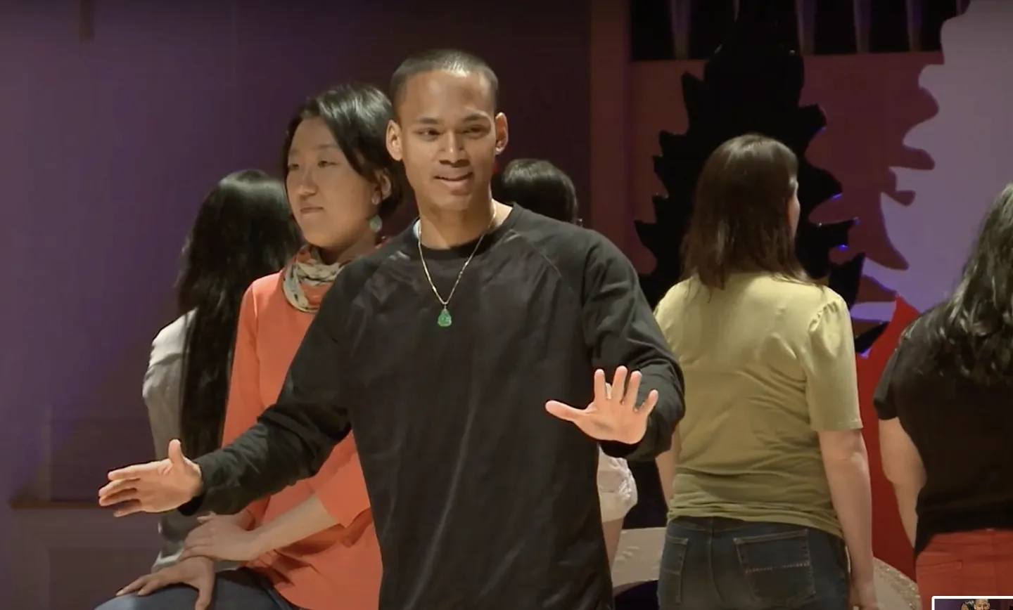 Young man in dark sweater with hands out.