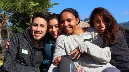 Four students hugging each other outside