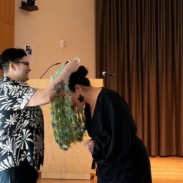 Person awarding a student and placing a lei over their head.