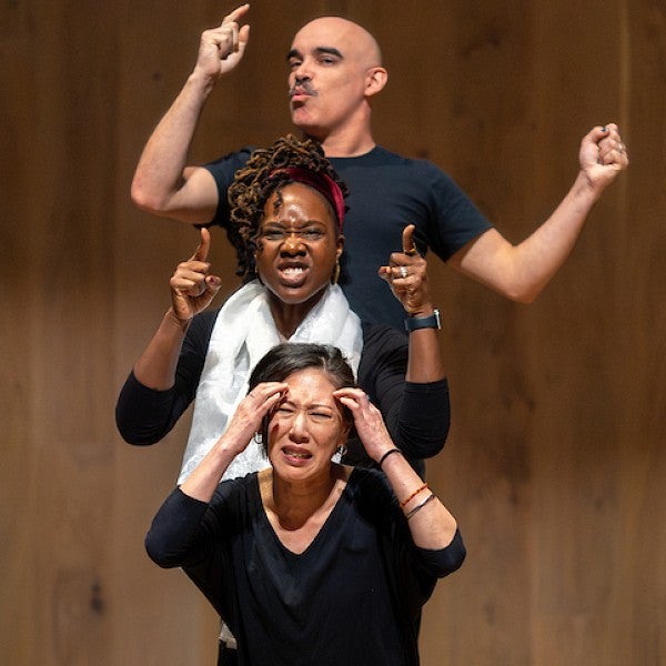 Four actors performing on stage with expressive hand gestures.