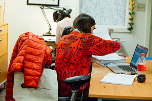 Person in red coat working at a desk