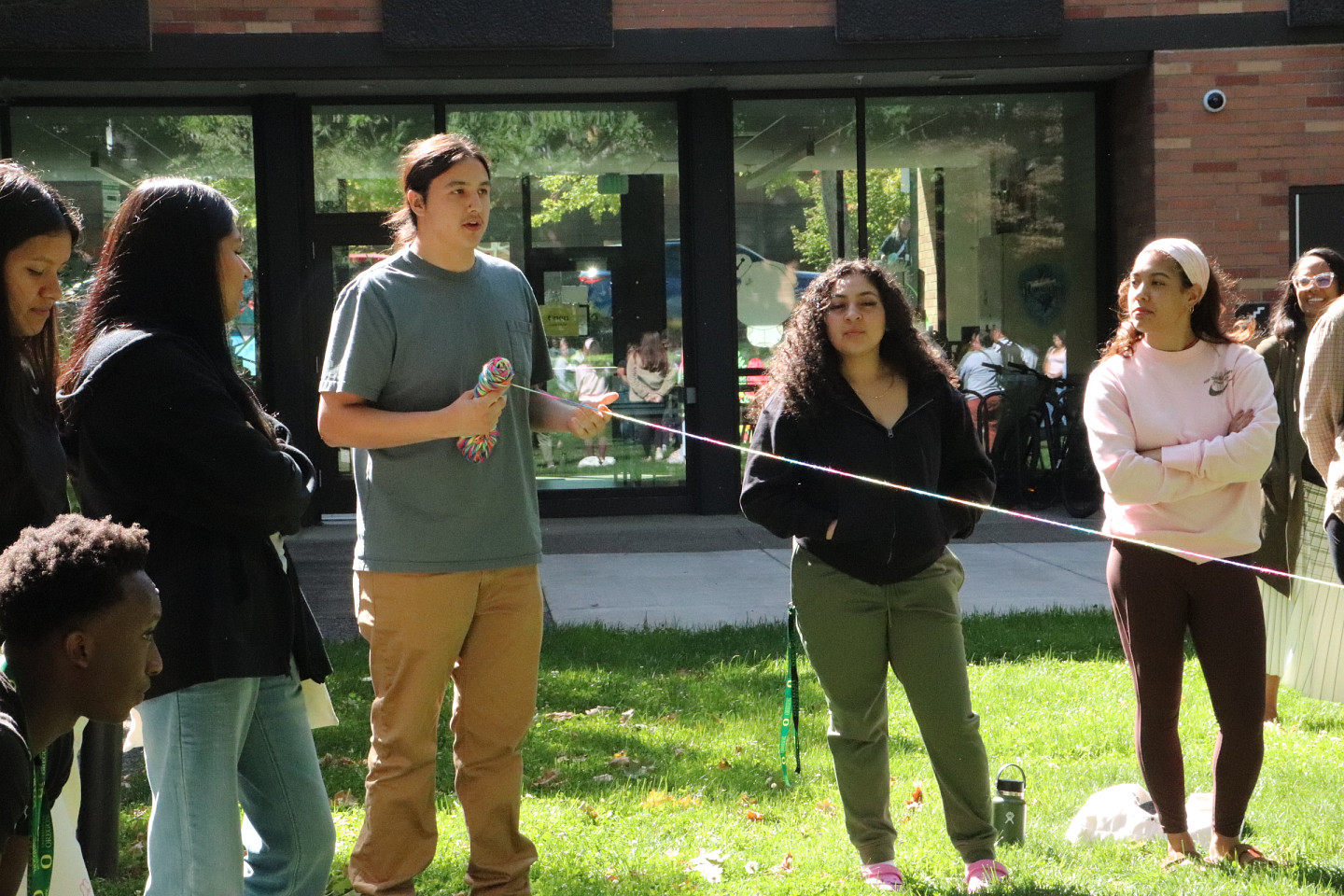 Students do a connection activity with yarn on a green lawn