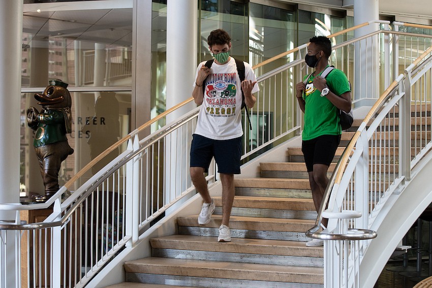 Two students with masks on walking down steps in the EMU