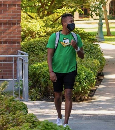 Student with mask walking outside on campus