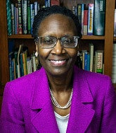 Yvette Alex Assensoh in pinkish jacket in front of bookscase