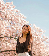 Joann Wu outside in front of pink flowering tree